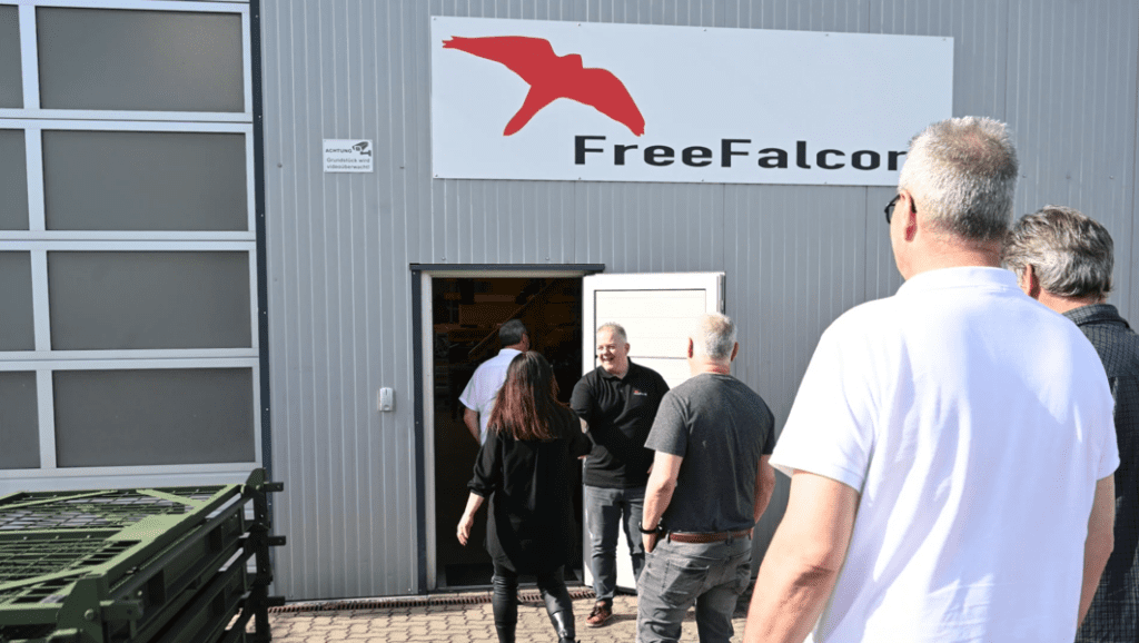 People entering a building with a sign that reads "FreeFalcon" and features a red bird logo, eager to engage in learning opportunities that await inside.